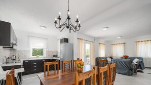 Una cocina moderna con comedor, que cuenta con una lámpara de araña, mesa de madera y sillas.