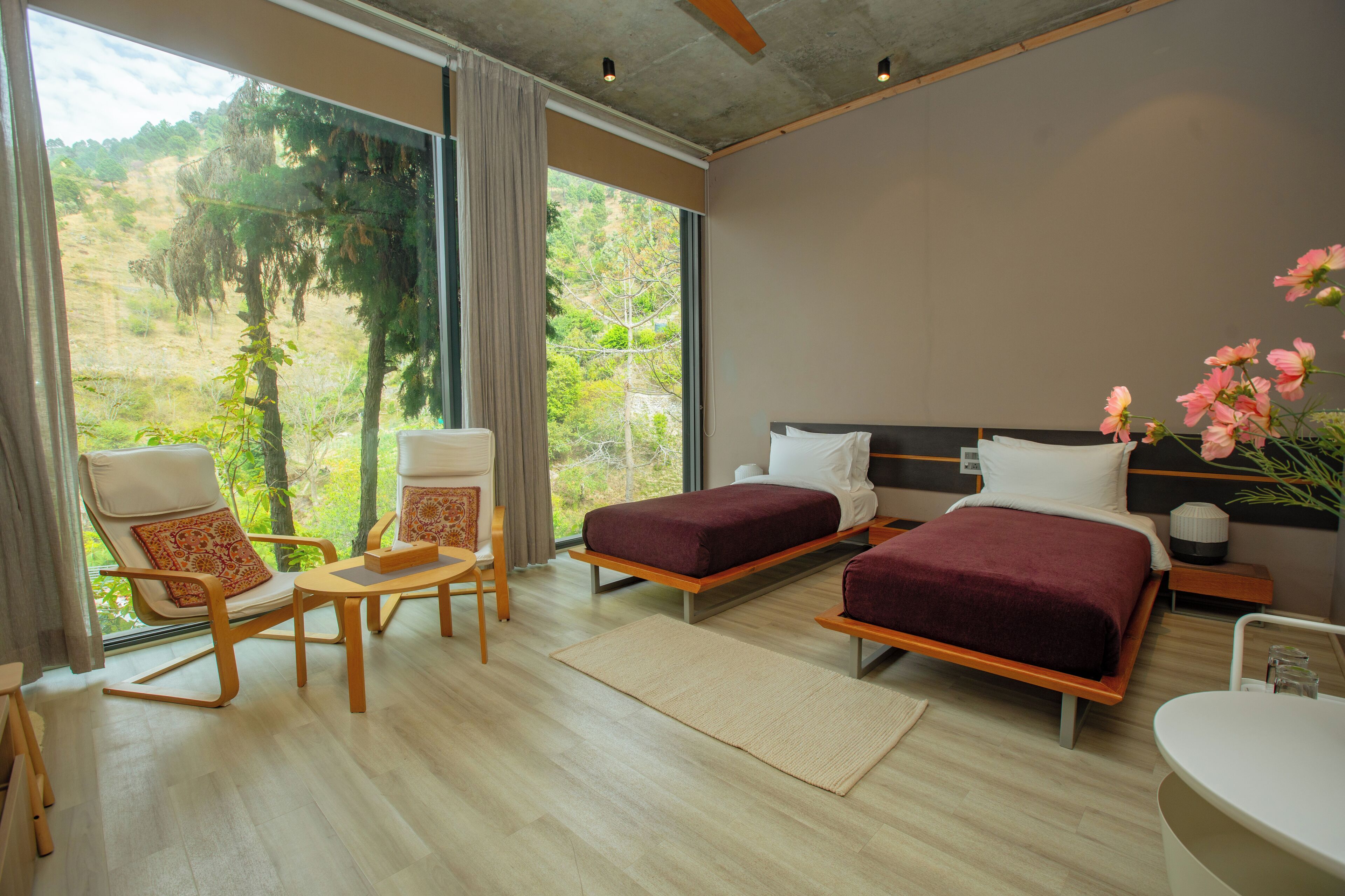 Une chambre moderne avec deux lits, un coin salon et une vue sur l’extérieur.