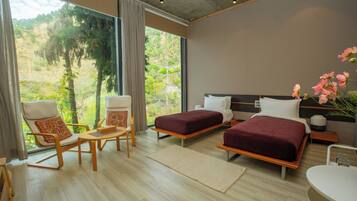 Un dormitorio moderno con dos camas, una zona de estar y vistas al exterior.