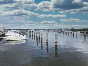 Un port de plaisance avec des bateaux amarrés à des poteaux en bois, une eau calme et un ciel dégagé.