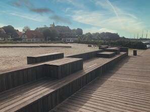 Une promenade en bois menant à une plage de sable, avec des marches et des bancs.