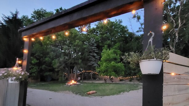 A wooden pergola with string lights, a potted plant, and a small statue. - Enjoyable 2 bedroom apartment with hot tub access.  (South Wales)