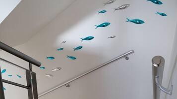 A staircase with a metal handrail and a wall with fish decals.