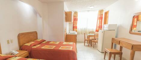 Quarto de hotel com duas camas, uma escrivaninha, uma cadeira, micro-ondas e frigorífico.