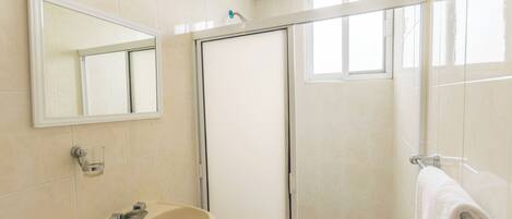 A bathroom with a sink, mirror, and shower.
