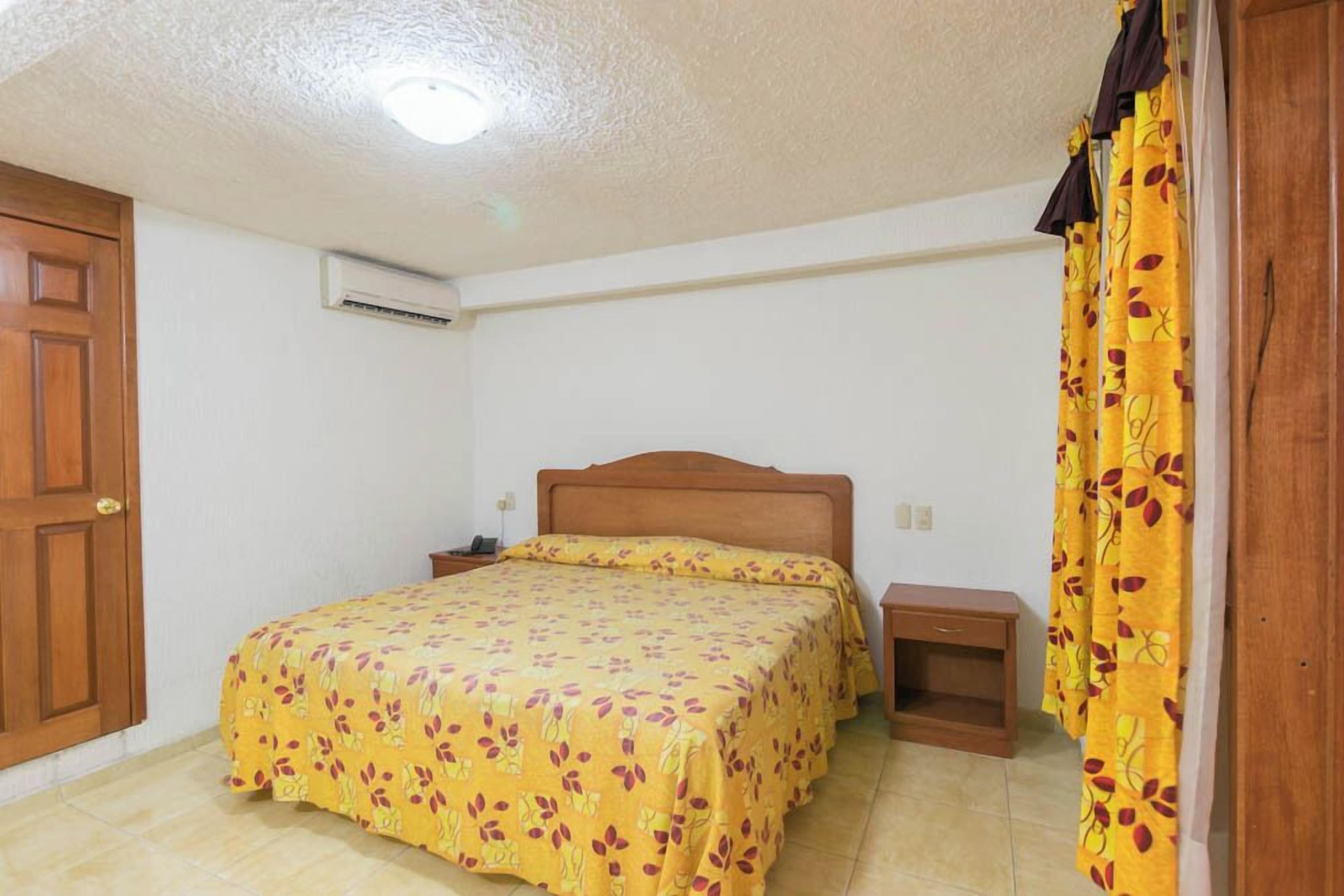 A bedroom with a bed, nightstands, a wooden door, and a curtain.
