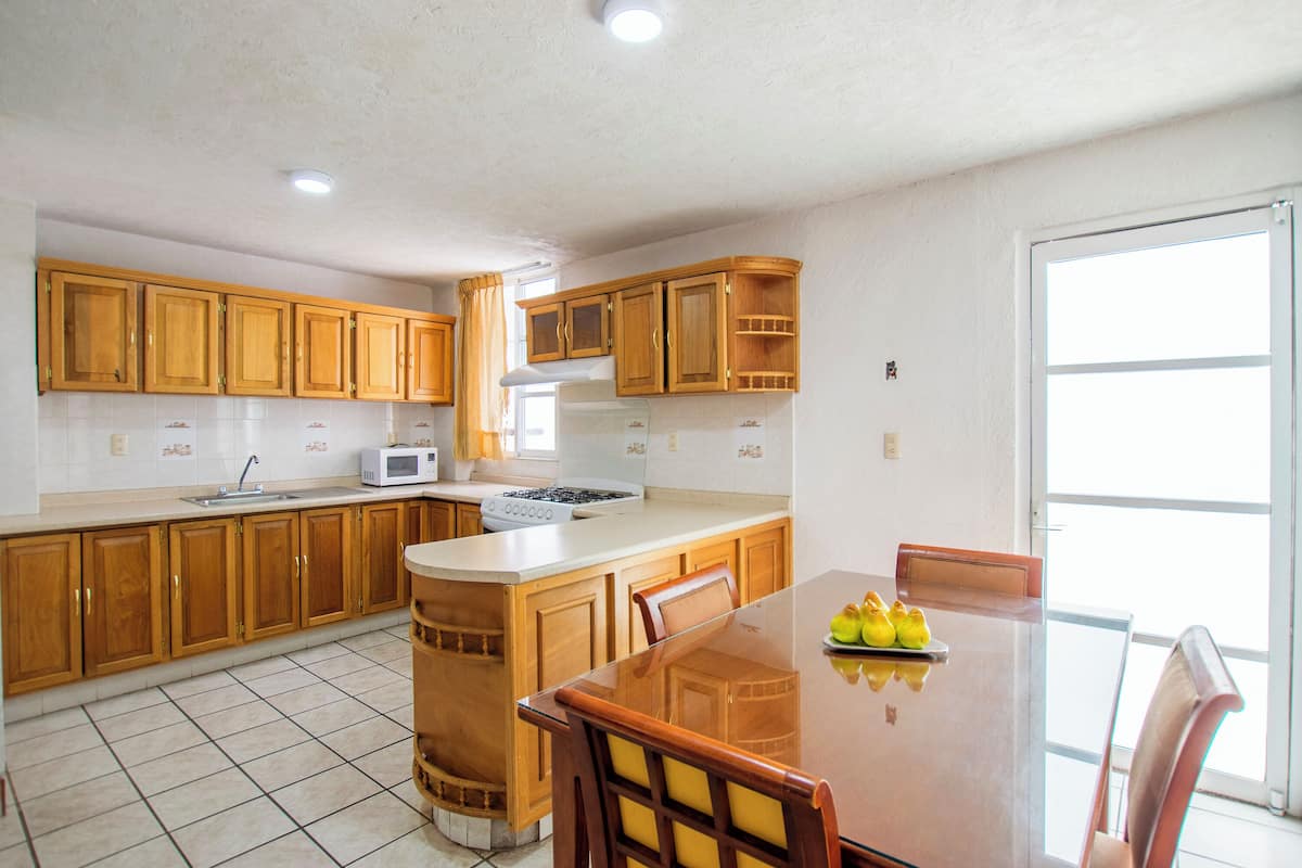 A kitchen with wooden cabinets, a microwave, a stove, and a dining table with chairs.