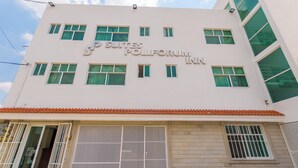 A hotel named 'Suites Poliforum Inn' with multiple windows and a tiled roof.
