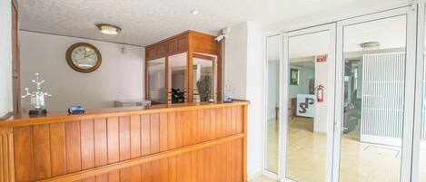 A reception area with a wooden counter, a clock, and a sliding glass door leading to another room.