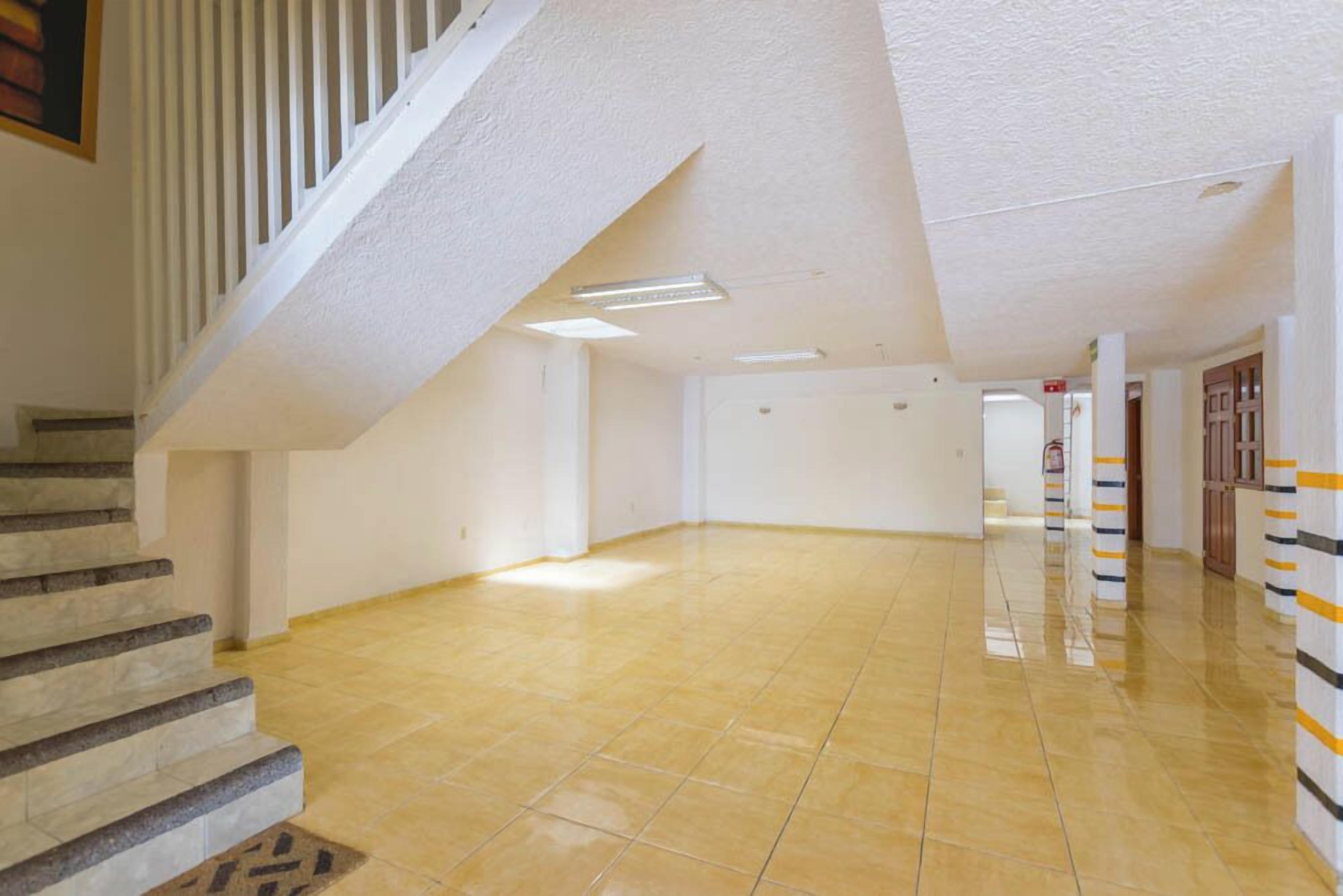 A spacious, well-lit hallway with a tiled floor and a staircase leading upwards.
