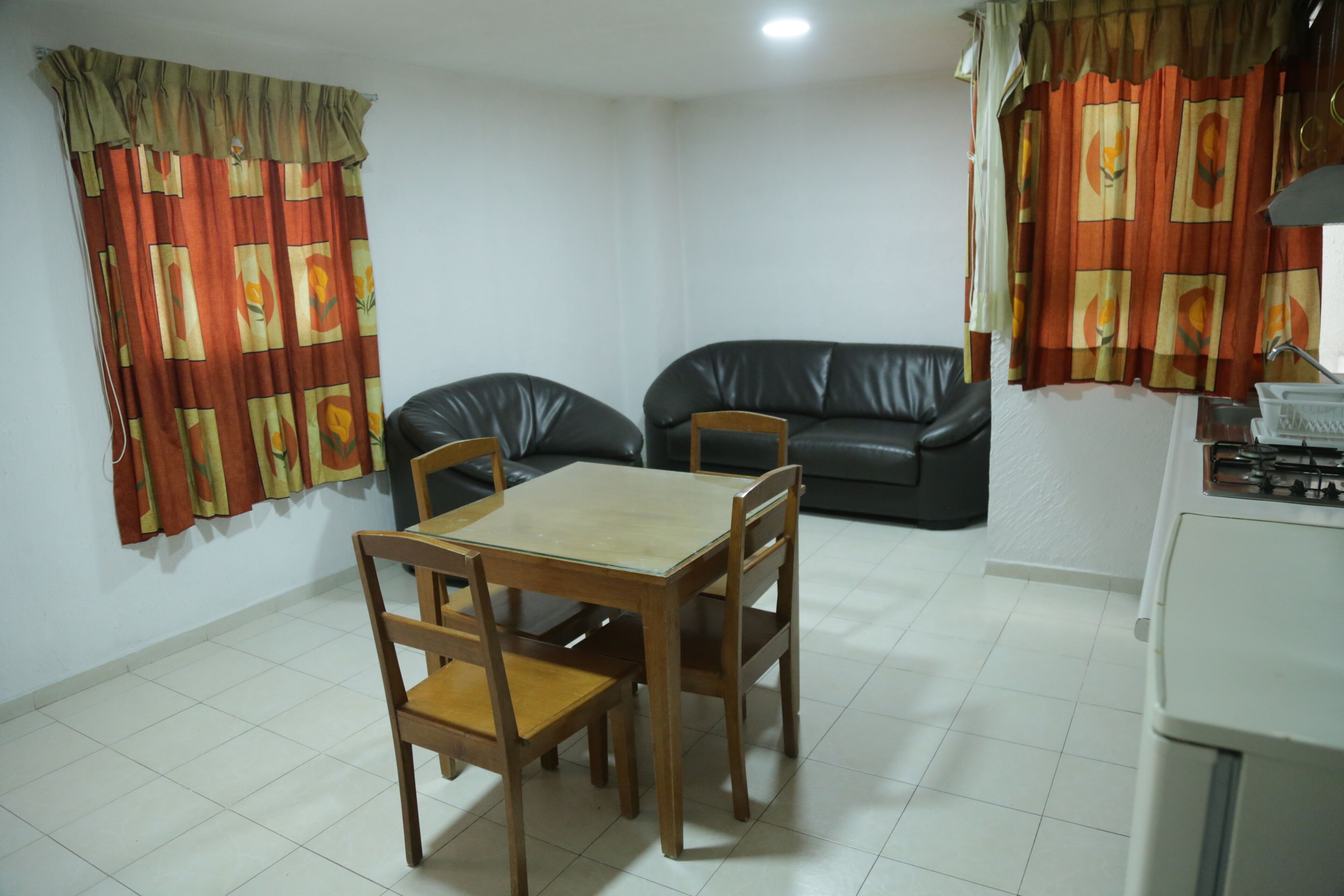 Un espacio habitable compacto con una mesa y sillas de comedor, un sofá y una kitchenette.
