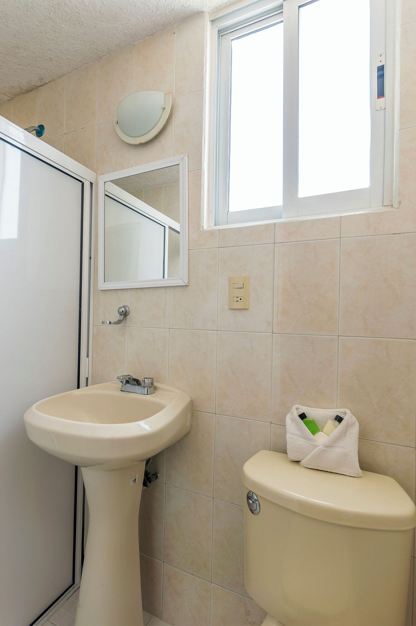 A bathroom with a sink, toilet, and a window.