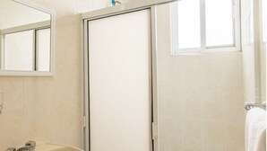 A bathroom with a sink, mirror, and a shower door.