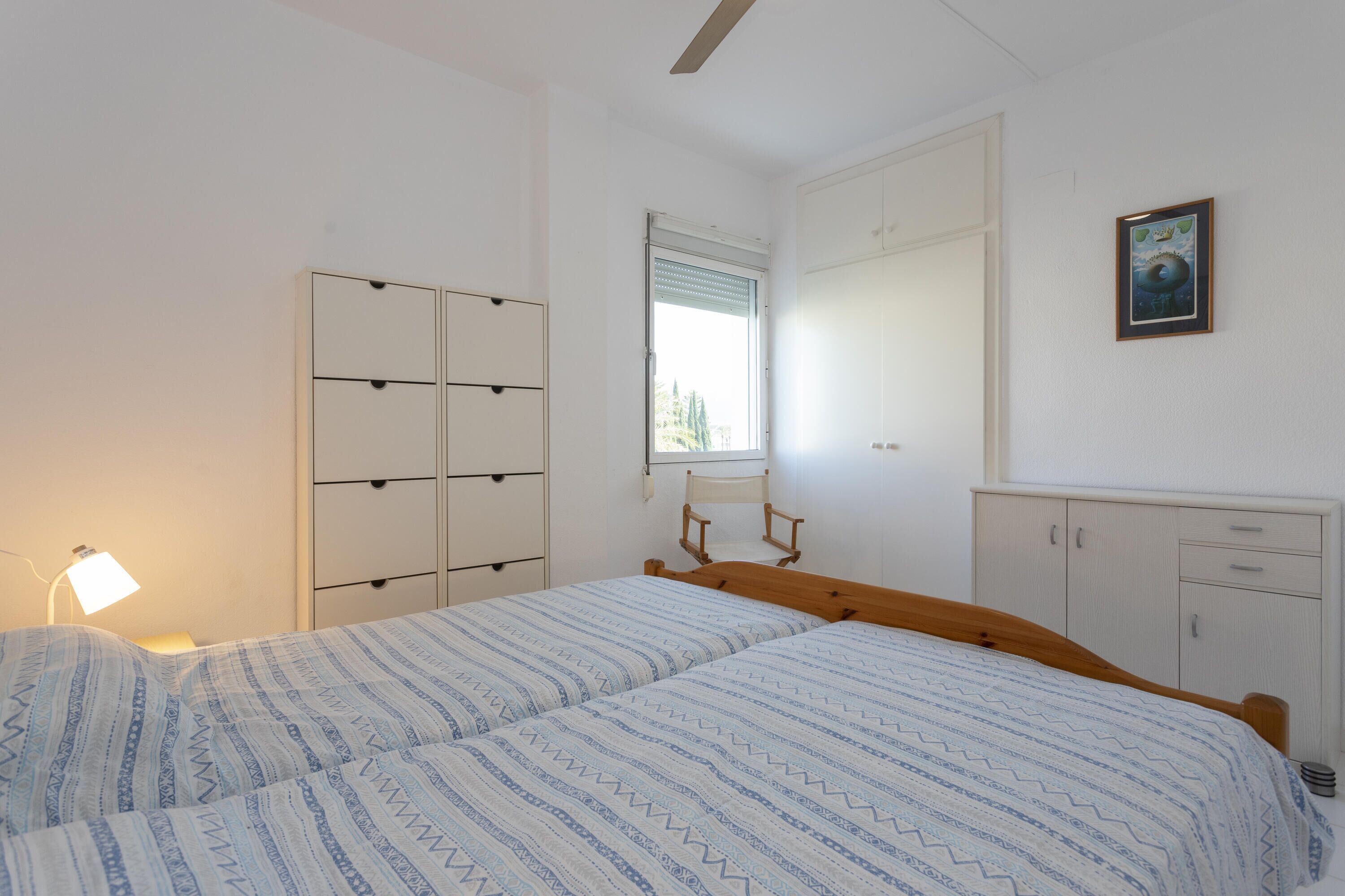 Une chambre à coucher avec un lit, une table de chevet, une armoire, une fenêtre et un tableau au mur.