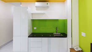 A compact kitchen with white cabinets, a black countertop, a green backsplash, and a yellow ceiling. - Tran Chau Hotel Q4 SG - by BAY LUXURY (Ho Chi Minh City)