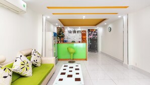 A hotel lobby with a reception desk, a green cushioned seating area, and a tiled floor. - Tran Chau Hotel Q4 SG - by BAY LUXURY (Ho Chi Minh City)