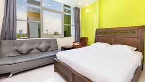 A bedroom with a bed, a grey sofa, a chair, and a window with curtains. - Tran Chau Hotel Q4 SG - by BAY LUXURY (Ho Chi Minh City)