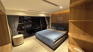 Camera da letto moderna con un letto grande, un comodino, un armadio a muro e vista sulla città da finestre a tutta altezza.