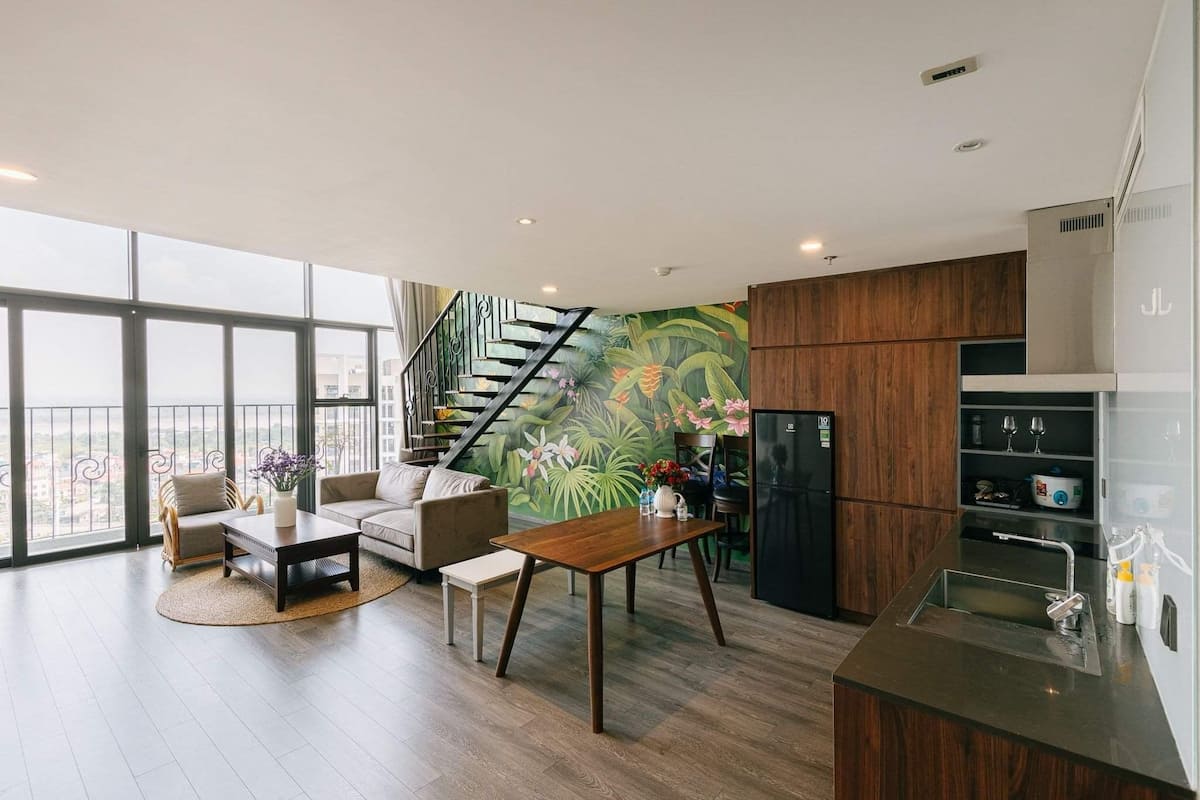 A modern living room with a sofa, coffee table, and a staircase leading to a balcony.