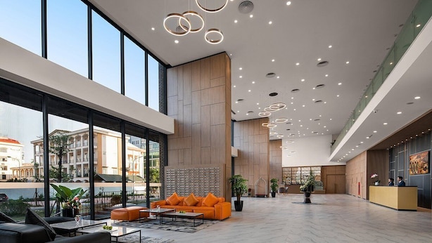 Un'ampia hall con reception, area relax e grandi finestre che offrono vista sulla città.