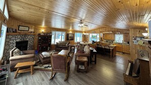 A spacious living room with a stone fireplace, wooden ceiling, and a cozy seating area. - Family-Friendly Cottage with all the Amenities You Need!  (Burk's Falls)