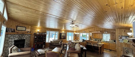 A spacious living room with a stone fireplace, wooden ceiling, and a cozy seating area.