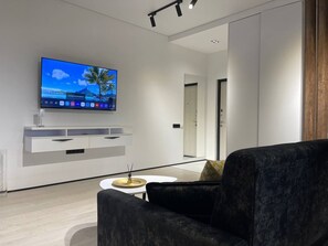 Suíte estúdio família, sacada, vista para a cidade | Área de estar | TV de tela plana 43 polegadas com canais digitais, TV