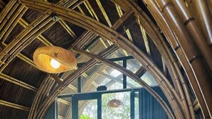 A room with a bed, a hanging light fixture, and a view of a garden through a glass door. - Hizo Garden Resort (Ea Nuol)