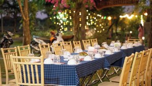 An outdoor dining area with tables set for a meal, surrounded by chairs. - Hizo Garden Resort (Ea Nuol)