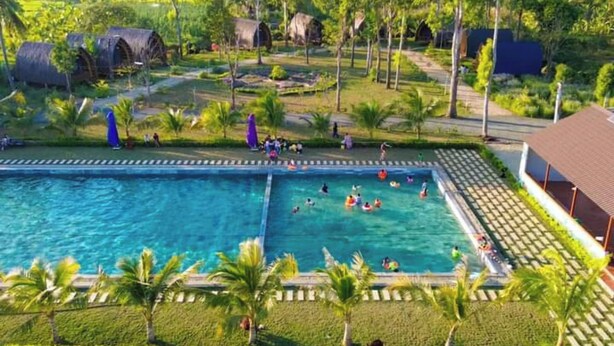A swimming pool surrounded by palm trees and a garden. - Hizo Garden Resort (Ea Nuol)