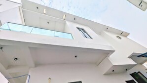 A modern building with a flat roof, multiple windows, and a visible air conditioning unit. - 4-Bedroom Duplex with Private Bathrooms in all Rooms (Lekki-Ajah Express Way)