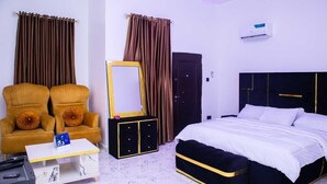 A hotel room with a bed, two armchairs, a small table, a cabinet, a mirror, and curtains. - 4-Bedroom Duplex with Private Bathrooms in all Rooms (Lekki-Ajah Express Way)