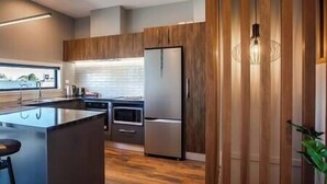 A modern kitchen with a central island, stainless steel appliances, and wooden paneling.