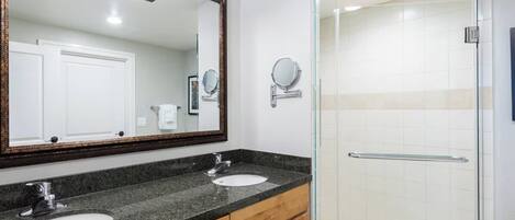 Un baño moderno con dos lavamanos, un espejo grande y una cabina de ducha de vidrio.