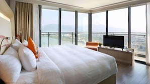 Une chambre d’hôtel moderne dotée d’un grand lit, d’une télévision et d’un balcon offrant une vue sur la ville.