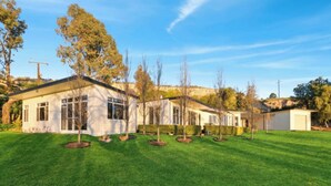 A modern house with a well-maintained lawn, multiple windows, and a garage. - On The Bend- Absolute Waterfront Retreat (Tailem Bend)