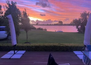 Une terrasse avec vue sur un lac au coucher du soleil.