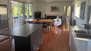 A modern kitchen with a central island, a dining area with a table and chairs, and a living space with a sofa and TV. - On The Bend- Absolute Waterfront Retreat (Tailem Bend)