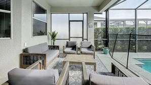 Eine sonnendurchflutete Terrasse mit Sitzgelegenheit, einem Pool und Blick ins Freie.
