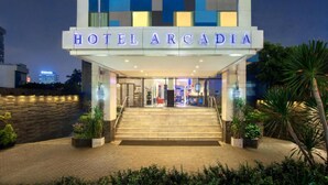 The exterior of Hotel Arcadia with a modern design, featuring a prominent entrance and a staircase leading to the lobby. - Horison Arcadia Wahid Hasyim (Jakarta)