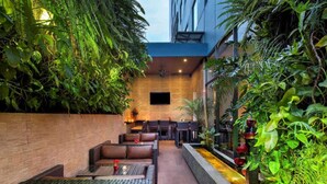 An outdoor seating area with wicker furniture and a small water feature. - Horison Arcadia Wahid Hasyim (Jakarta)