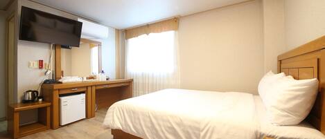 Ein Hotelzimmer mit Bett, Schreibtisch, Fernseher und einer kleinen Küchenzeile.