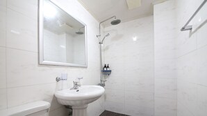 Un baño con lavamanos pedestal, cabezal de ducha manual, inodoro y espejo.