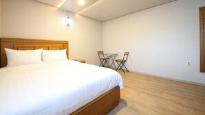 Un dormitorio con una cama grande, una mesita con sillas y una lámpara en el techo.