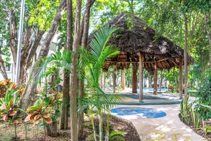 A thatched-roof structure surrounded by trees and plants. - Playa House 4 Bedrooms Pool and More (Playa del Carmen)
