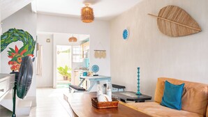 Un salon moderne avec une table basse en bois, un canapé agrémenté d’un coussin bleu et une horloge fixée au mur.