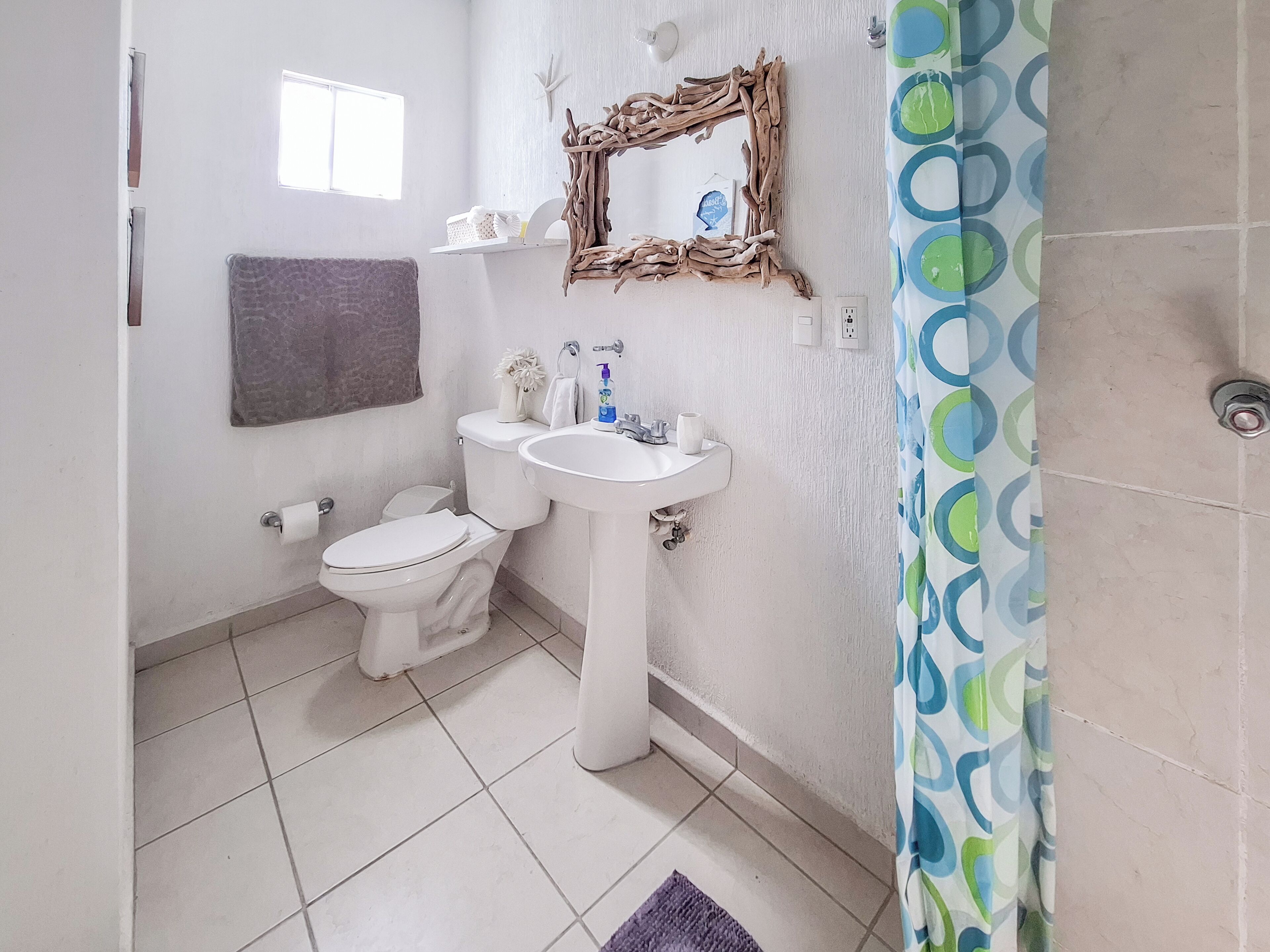 Un baño con inodoro, lavamanos y un espejo decorativo.
