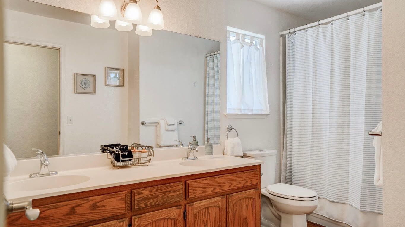 A bathroom with a wooden vanity, a large mirror, and a shower curtain.