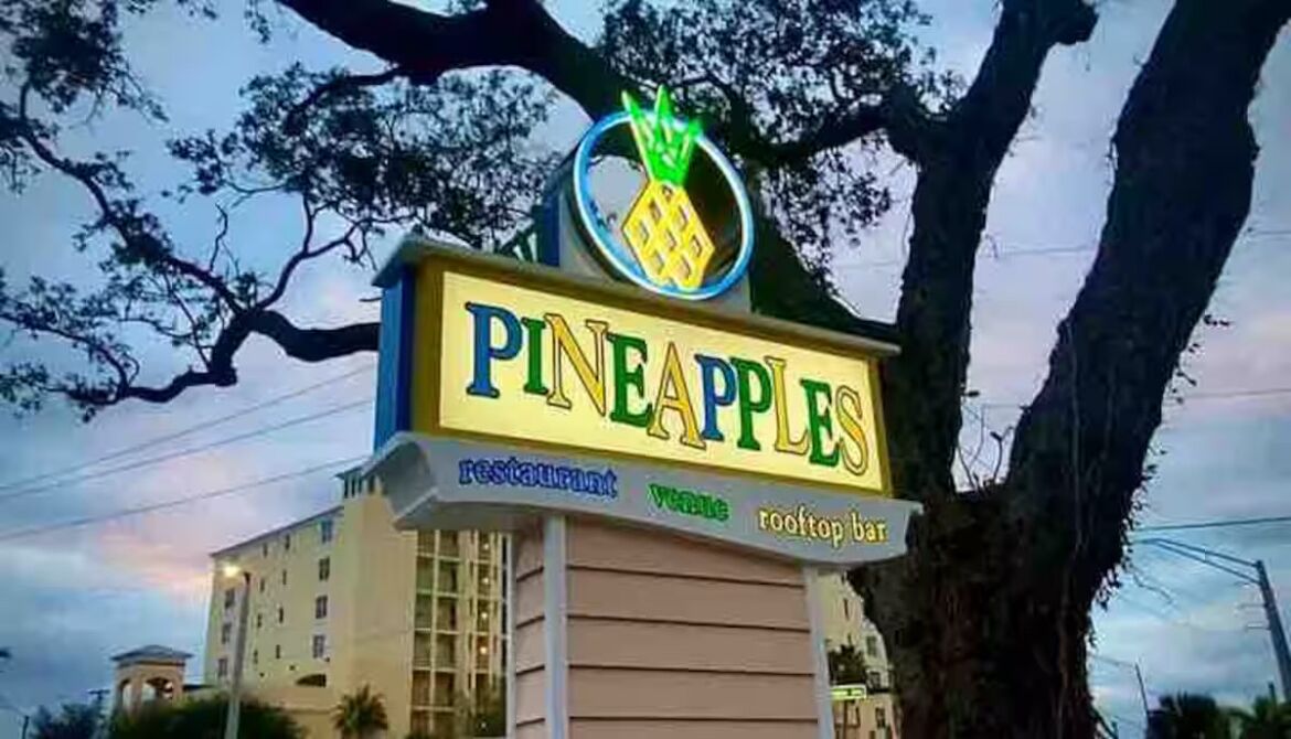 Señal de restaurante llamado "Pineapples" con logotipo de piña.