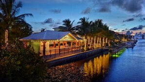 A waterfront restaurant with a covered patio, palm trees, and a dock extending into the water. - RV in Art District and Close to the BEACH! Pool & Hot-Tub & Fenced/Pet-Friendly! (Melbourne)